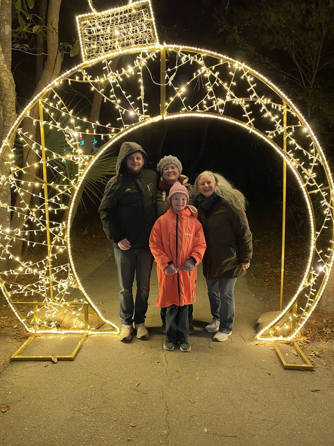Family together beneath a holiday light display