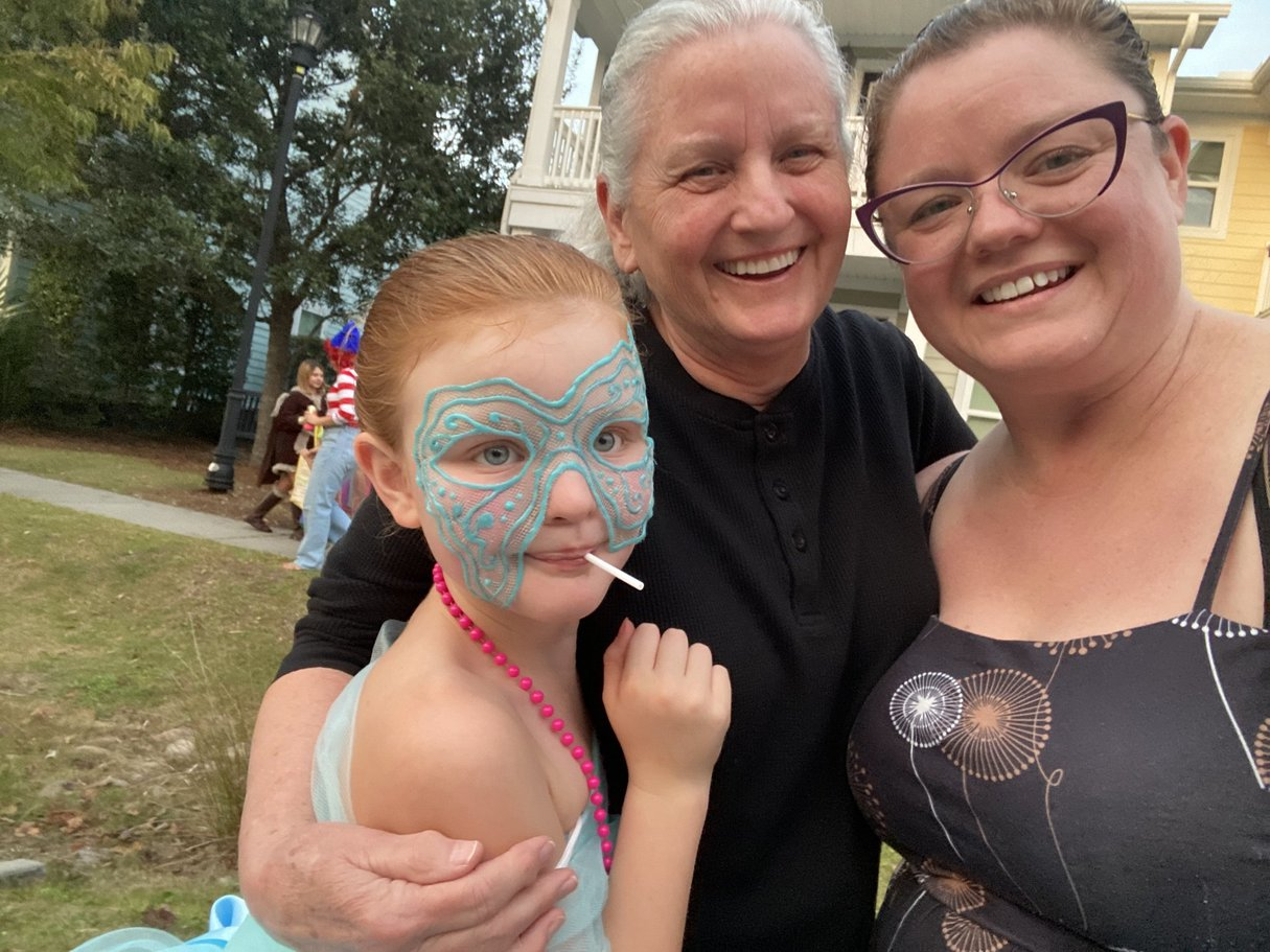 Three family members smiling together outdoors